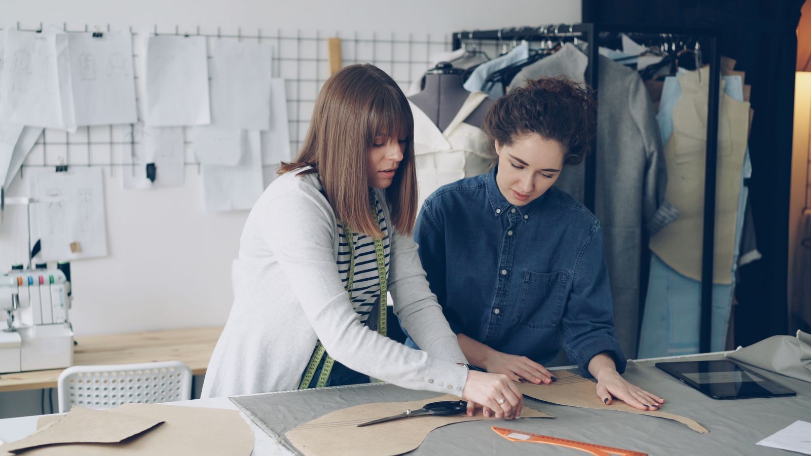 Two women working together at a sewing table in a workshop